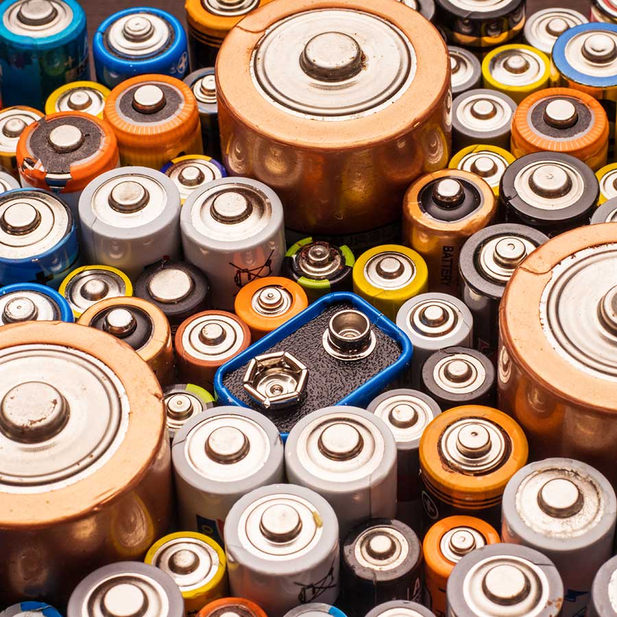 Close-up view of various types and sizes of batteries, including AA, AAA, D, and a 9V battery, arranged closely together with their terminals facing up.